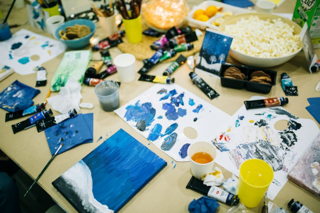 Children sit at large table and draw pictures in art master class, learning to draw, creative mess