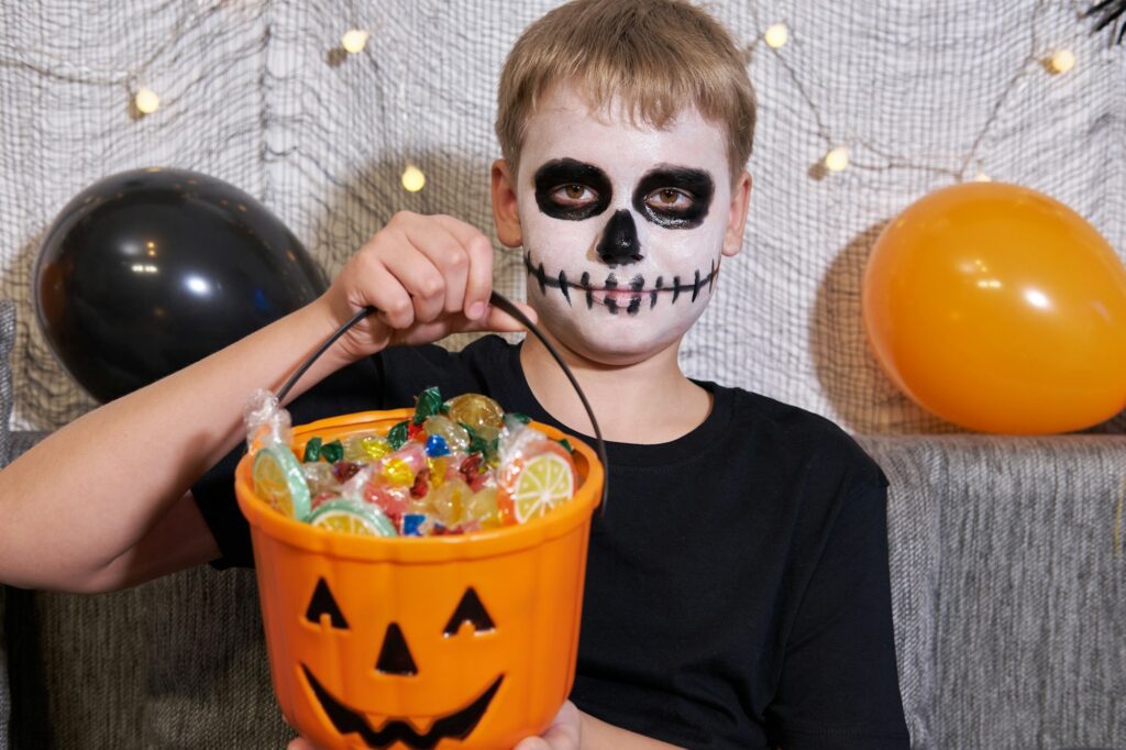 The child takes out the candy from the bucket for Halloween